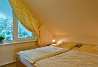 Chambre confortable avec deux lits simples et grande fenêtre au Vakantiepark Havelberge, en Mecklembourg-Poméranie.