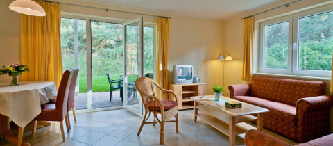 Sala luminosa en alojamiento glamping con sofá, comedor y vistas al jardín en Vakantiepark Havelberge.