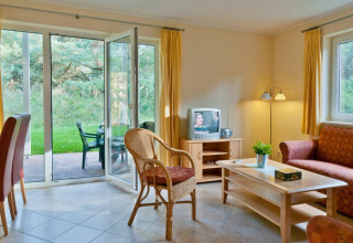 Helles Wohnzimmer in einem Glamping-Haus mit Sofa, Essecke und Blick ins Grüne im Havelberge Park.