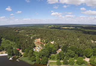 Vue aérienne du glamping et camping Vakantiepark Havelberge entouré de forêt et d’eau en Mecklembourg-Poméranie.