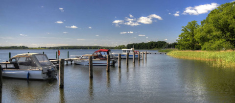 Boote liegen an einem Steg im ruhigen Wasser bei Vakantiepark Havelberge in Mecklenburg-Vorpommern.