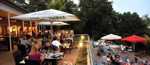 Udendørs spisested på Vakantiepark Havelberge, Mecklenburg-Vorpommern, omgivet af natur og gæster.