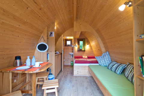 Interior view of a cozy wooden glamping lodge at Campingpark Kerstgenshof, showing bed and seating.
