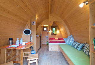 Intérieur confortable d'un lodge en bois au Campingpark Kerstgenshof, avec lit, banc et coin repas.