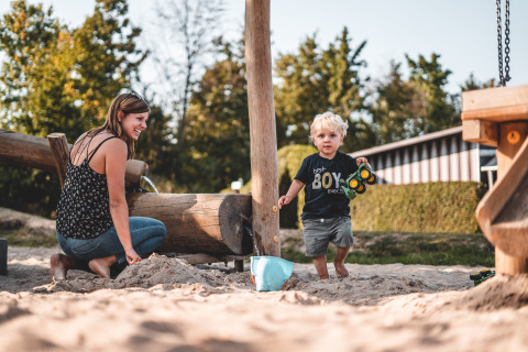 Mère et enfant jouant ensemble dans le bac à sable au Campingpark Kerstgenshof - Lodges Duitsland en plein air.
