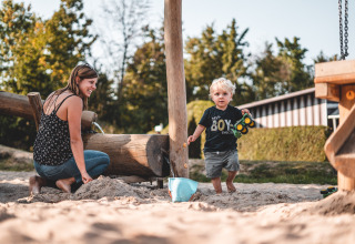 Mère et enfant jouant ensemble dans le bac à sable au Campingpark Kerstgenshof - Lodges Duitsland en plein air.