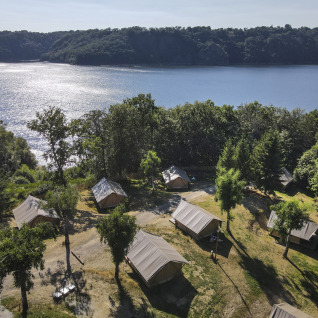 Tentes de glamping luxueuses au bord du lac à Huttopia Lac de la Siauve - Glamping Auvergne, entourées de forêt.