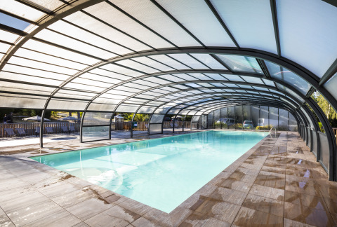 Overdækket swimmingpool med gennemsigtigt tag på Huttopia Lac de la Siauve Glamping i Auvergne, Frankrig.