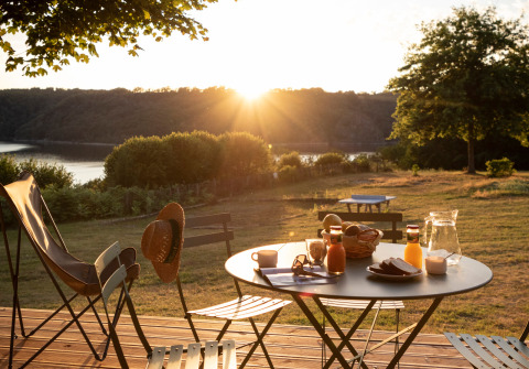 Colazione in terrazza con vista lago all’alba presso Huttopia Lac de la Siauve - Glamping Auvergne.