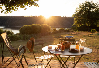 Desayuno en una terraza con vistas al lago al amanecer en Huttopia Lac de la Siauve - Glamping Auvergne.
