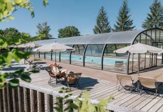 Outdoor pool area with lounge chairs and umbrellas at Huttopia Lac de la Siauve - Glamping Auvergne in summer.