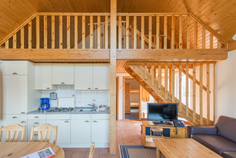 Interno di un moderno cottage glamping in legno con soppalco e cucina al Südsee-Camp in Bassa Sassonia.