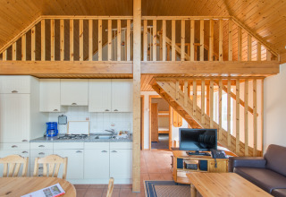 Vue intérieure d’un cottage glamping moderne en bois avec mezzanine et cuisine au Südsee-Camp.
