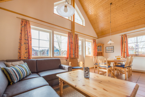 Bright living and dining area in a luxe cottage at Camping Südsee-Camp, Lower Saxony, with wooden ceilings.
