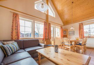 Acogedora sala-comedor en cabaña de lujo en Camping Südsee-Camp en Niedersachsen, con techos de madera.