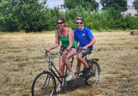 To personer nyder en tandemcykeltur på en mark ved Stadslandgoed De Heicohoeve - Glamping Lodges Gelderland.