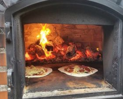 Wood-fired pizza oven in use at Stadslandgoed De Heicohoeve - Glamping Lodges Gelderland campsite.