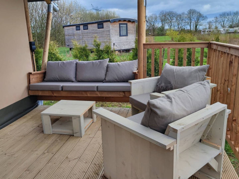 Gemütliche Terrasse mit Holzmöbeln bei Stadslandgoed De Heicohoeve - Glamping Lodges Gelderland.