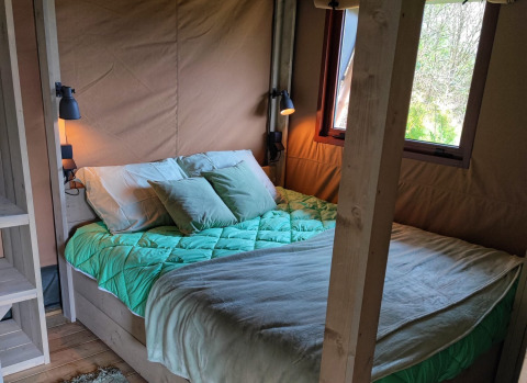 Lodge de glamping confortable avec lit douillet et fenêtre chez Stadslandgoed De Heicohoeve en Gelderland.