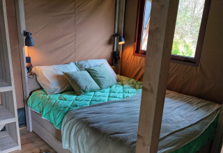 Gemütliche Glamping-Unterkunft mit bequemem Bett und großem Fenster bei Stadslandgoed De Heicohoeve in Gelderland.
