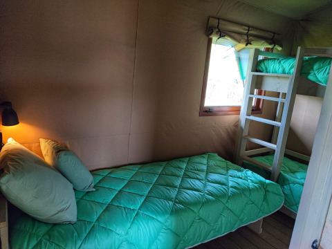 Interior of a cozy glamping lodge at Stadslandgoed De Heicohoeve in Gelderland with single and bunk beds.