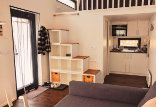 Interior of Tiny lodge - Ellertshäuser See showing compact kitchen, stairs, cozy entrance and loft area.
