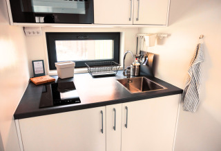 Moderne, compacte keuken in glampingaccommodatie Tiny lodge - Ellertshäuser See met wasbak en kookplaat.