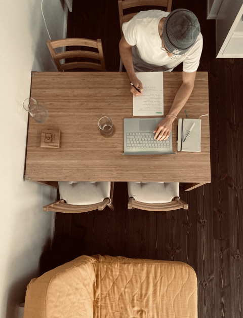 Bovenaanzicht van een persoon aan tafel met laptop en notities in Tiny lodge - Ellertshäuser See glamping.