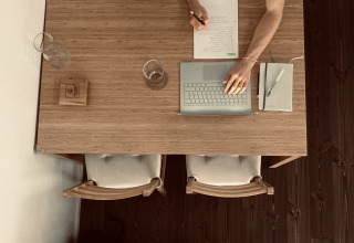 Top view of someone writing notes and using a laptop at a table in Tiny lodge - Ellertshäuser See glamping.
