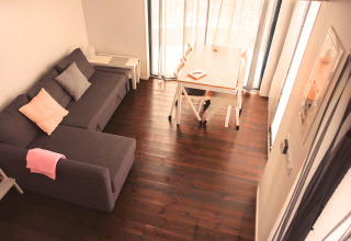 Modern living space in Tiny lodge - Ellertshäuser See glamping with gray sofa and dining table.