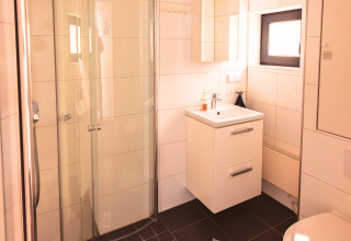 Moderne badkamer in Tiny Lodge - Ellertshäuser See met douche, toilet en wastafel, ideaal voor glamping.