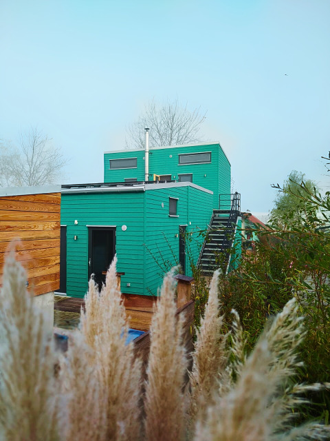 Groene glampingaccommodatie Tiny lodge - Ellertshäuser See met houten accenten en buitentrap.