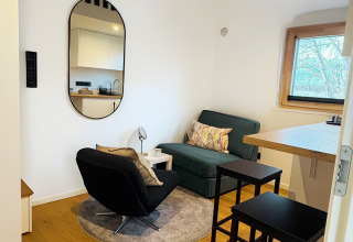 Modernes Tiny Lodge am Ellertshäuser See mit Sitzecke, Küchenzeile, Barhockern und Fensterblick.