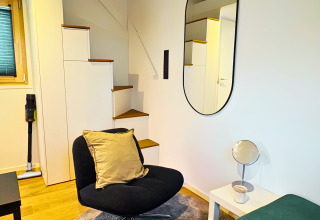 Modernes Interieur im Tiny Lodge am Ellertshäuser See mit gemütlichem Sessel und stilvoller Treppe.