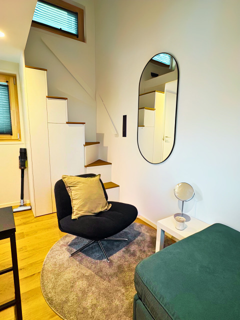 Modern interieur van Tiny lodge bij Ellertshäuser See met een comfortabele stoel en slimme trap.