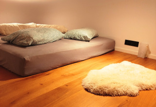 Cozy glamping accommodation at Tiny lodge - Ellertshäuser See, featuring a low bed and soft rug on wood floor.