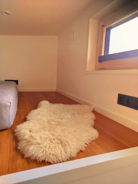 Knus hoekje met houten vloer, wit tapijtje en raam in Tiny Lodge aan het Ellertshäuser See.