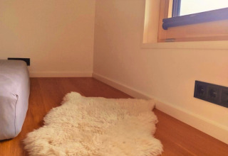 Cozy nook with wooden floor, fluffy white rug and window in Tiny Lodge accommodation at Ellertshäuser See.