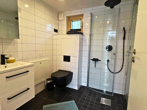 Moderne badkamer met zwart toilet, douche en witte tegels in Tiny Lodge bij Ellertshäuser See voor glamping.