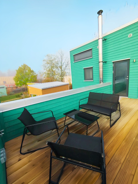 Terrasse mit modernen schwarzen Stühlen und Tisch vor einer grünen Hütte, Tiny lodge - Ellertshäuser See.