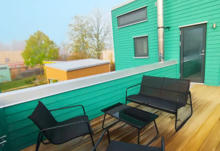 Outdoor terrace with modern black chairs and table at a green Tiny lodge - Ellertshäuser See glamping cabin.