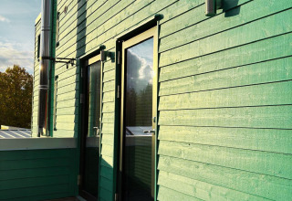 Udendørsbillede af Tiny Lodge ved Ellertshäuser See med grønne vægge, terrasse og moderne detaljer.