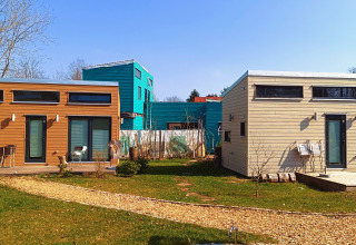 Accoglienti tiny house per glamping al 'Tiny lodge - Ellertshäuser See' con giardino e cielo sereno.