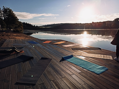 Tapis de yoga sur une terrasse en bois au bord du lac au lever du soleil, Tiny lodge - Ellertshäuser See.