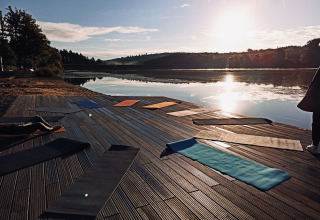 Yogamåtter på træterrasse ved søen i solnedgangen ved Tiny lodge - Ellertshäuser See, glamping.