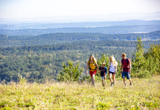 Familie på vandretur nær Tiny lodge - Ellertshäuser See, omgivet af smuk udsigt og grønne bakker.