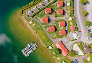 Vue aérienne de Vakantiepark Sorpesee - Boomhutten Noordrijn-Westfalen avec cabanes, lac, bateaux et parking.