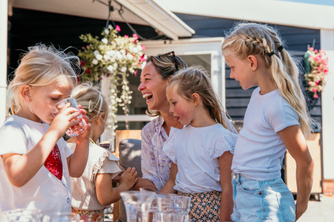 Familie nyder udendørs tid sammen ved Strandpark De Zeeuwse Kust - Safaritenten Zeeland på en solrig dag.