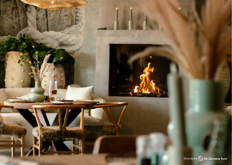 Inviting glamping accommodation at Strandpark De Zeeuwse Kust with cozy fireplace and elegant decor.