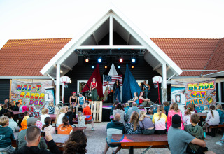 Familien genießen eine Freiluft-Theateraufführung auf dem Campingplatz Strandpark De Zeeuwse Kust.